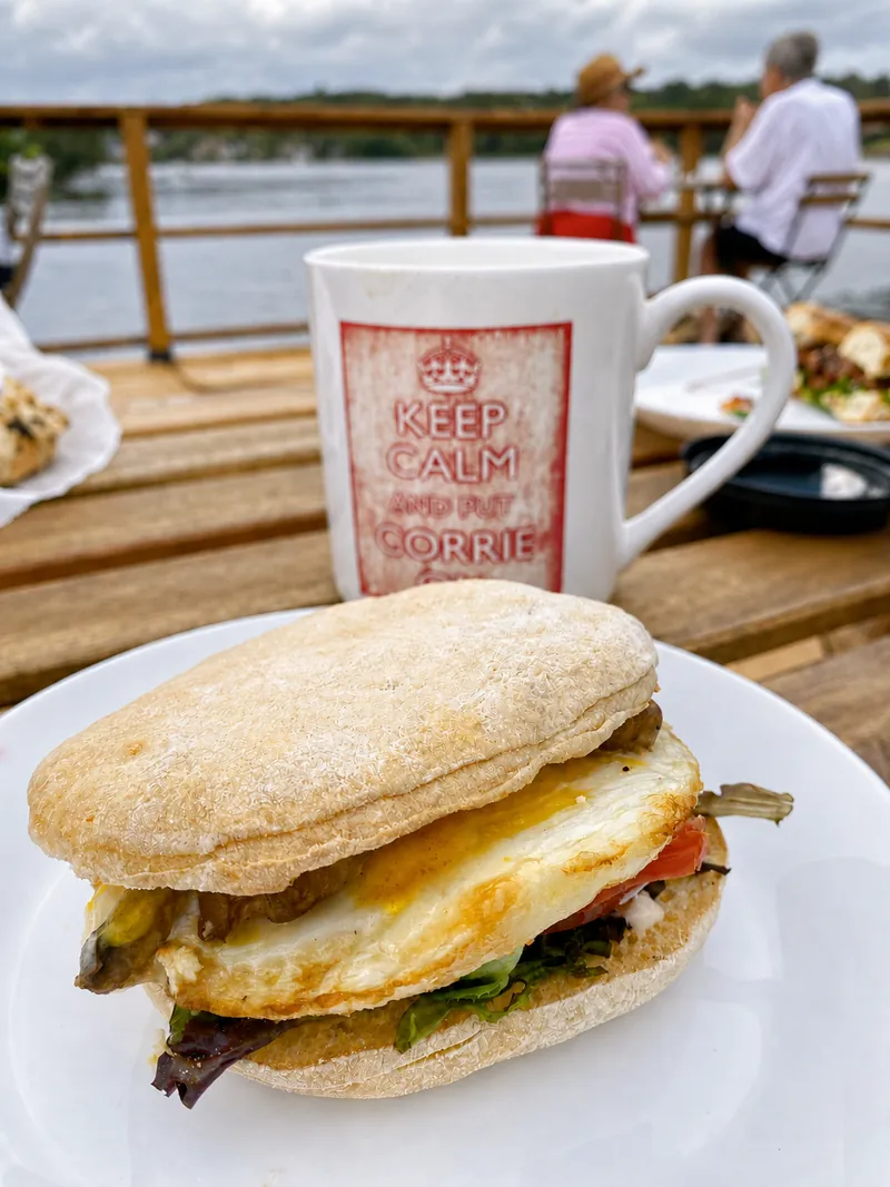A breakfast sandwich and a mug on the cafe’s lakeside deck.