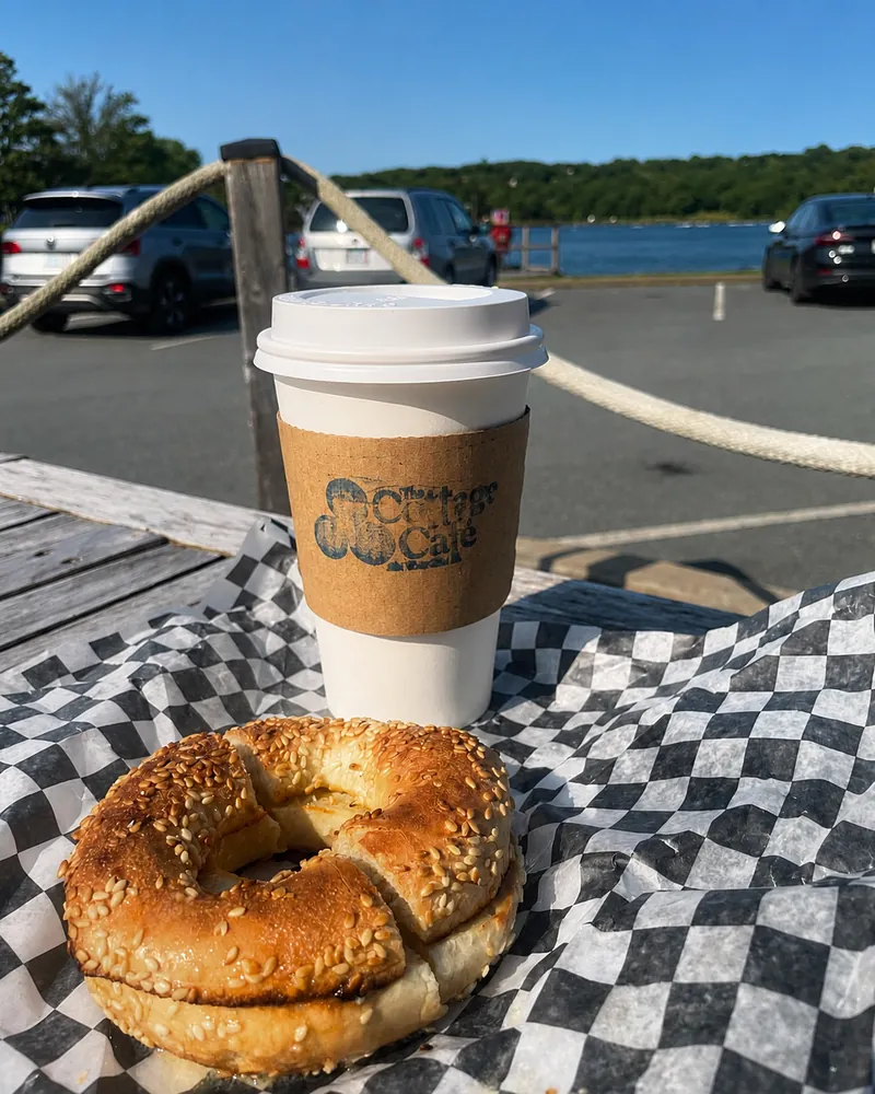 Cottage Cafe takeaway coffee and a bagel on an outdoor table.
